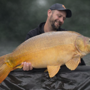 pêcheur et carpe miroir souriant